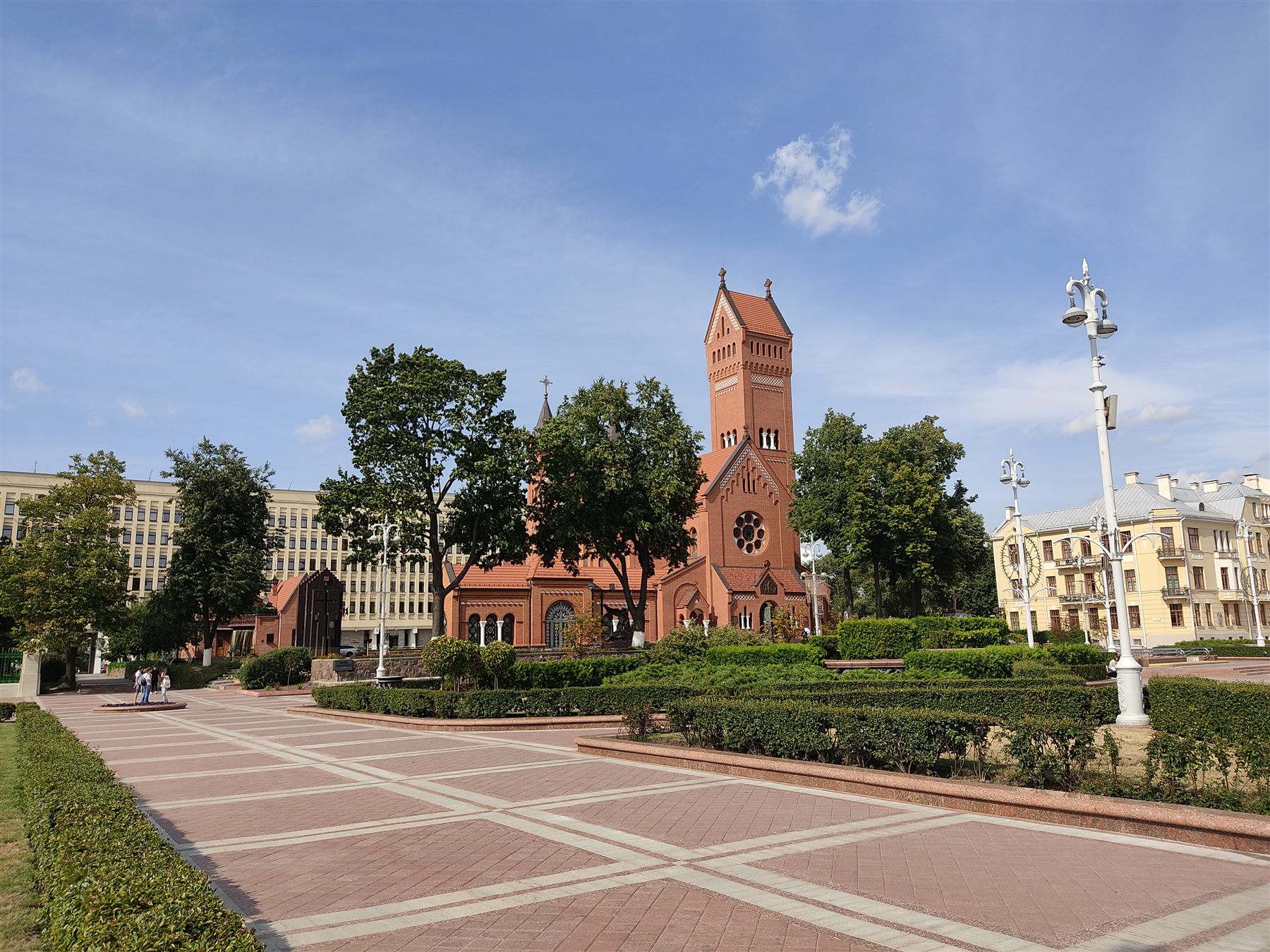 Красный костёл на площади Независимости среди деревьев